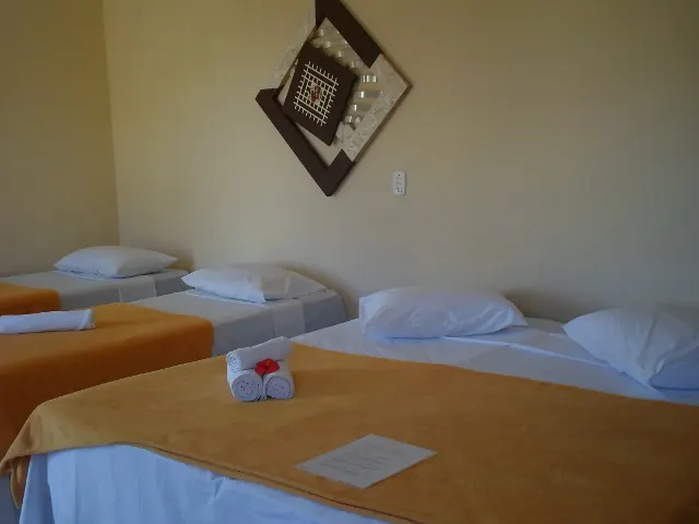 Quarto quádruplo com camas de solteiro, colchas laranja e enfeite na parede