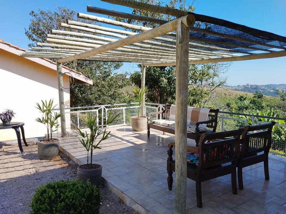 Terraço coberto com pergolado de madeira, poltronas e vista para o vale