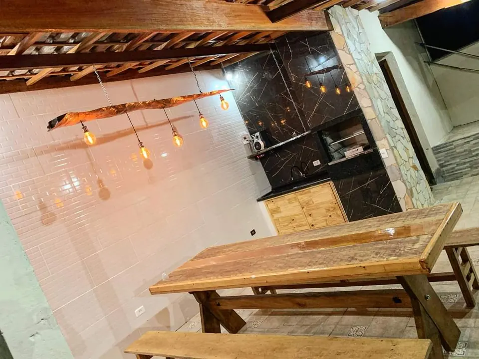 Interior do salão de refeições com teto de madeira, luminária rústica e mesa comprida